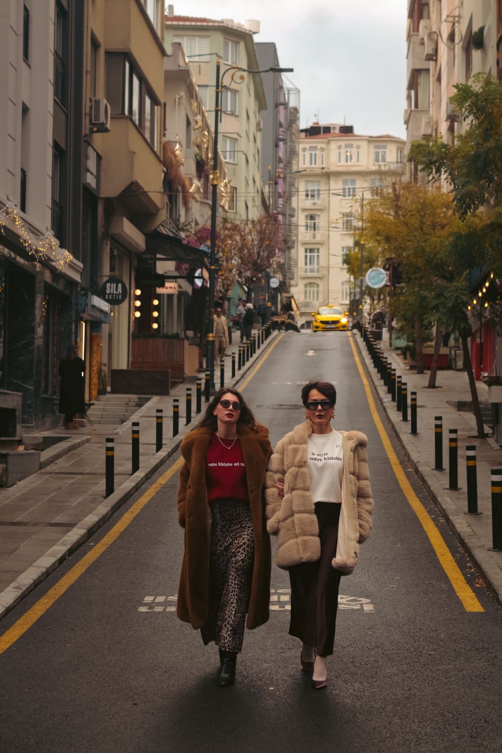 Two women walking through a city in long autumn coats