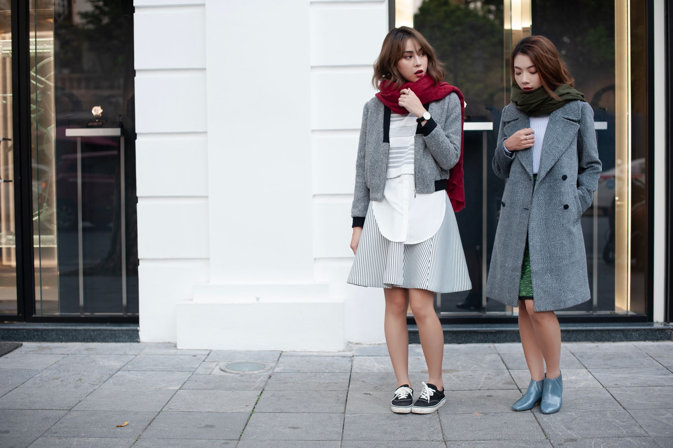 Two women in grey coats and colorful scarves